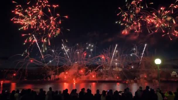 Brandbomben explodieren in der Luft. Menschenmassen schauen Feuerwerk an. 4k. — Stockvideo