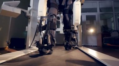 Bir koşu bandı yürüyüş bir exoskeleton içinde bir adam.