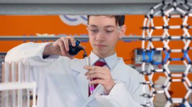 Bir okul çocuğu ölçer ve kimyasallar karışımları.