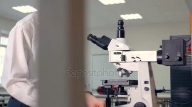 Genç bir bilim adamı bir optik mikroskobu kullanır.