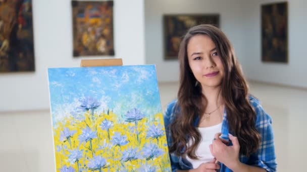 Portret. Kunstenaar glimlachend staande in de buurt van een foto van bloemen. — Stockvideo