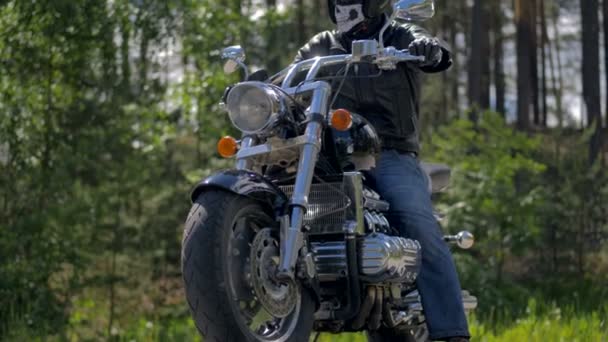 Pewni biker siedzi na motocyklu w lesie. — Wideo stockowe