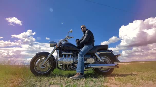 Вид чоловіка, що сидить на мотоциклі в сонцезахисних окулярах . — стокове відео