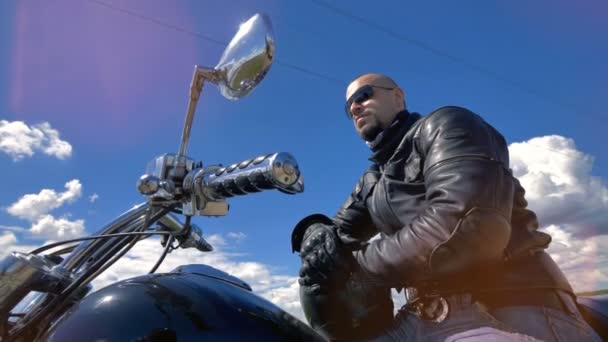 Une vue basse sur un motocycliste portant des lunettes de soleil noires. 4K . — Video