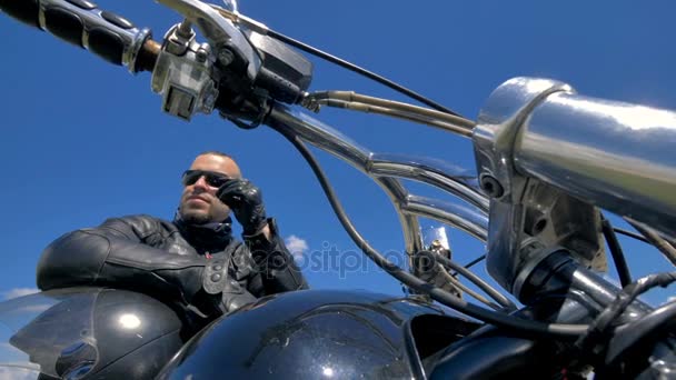 Biker, Motorradfahrer legt die Hände auf den Helm und streift seine Sonnenbrille. 4k. — Stockvideo