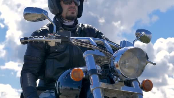 Um homem senta-se na bicicleta e tira um capacete. Retrato de motociclista . — Vídeo de Stock