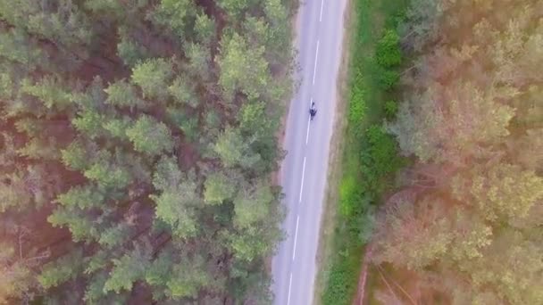 Une vue de dessus prise sur un motocycliste chevauchant une longue route étroite. 4K .