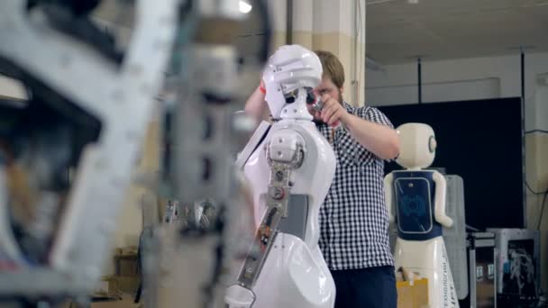 A young engineer disassembles a robots head. — Stock Video