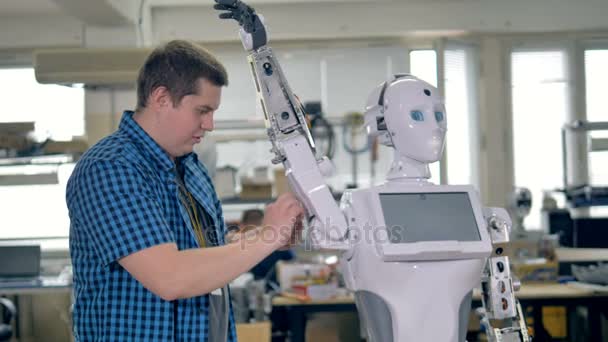 Trabajadores del taller ensamblan brazos de robots y la cabeza . — Vídeos de Stock