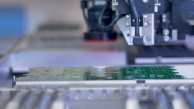 Yeşil bir devre kartı üzerinde hareketli bir Smt robot makine.