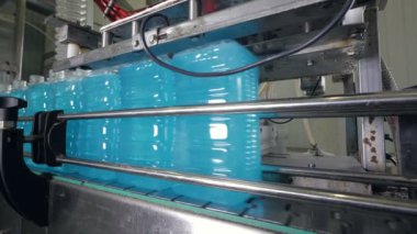 Konveyör bant üzerinde büyük dolu plastik kaplar.