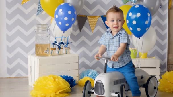 Un tout-petit est assis sur une voiture jouet blanc . — Video