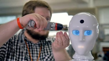 Robotlar kafa ile bir araç sabitleme bir adam.