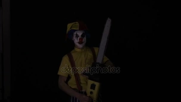 A clown comes out of the dark with a chainsaw. — Stock Video