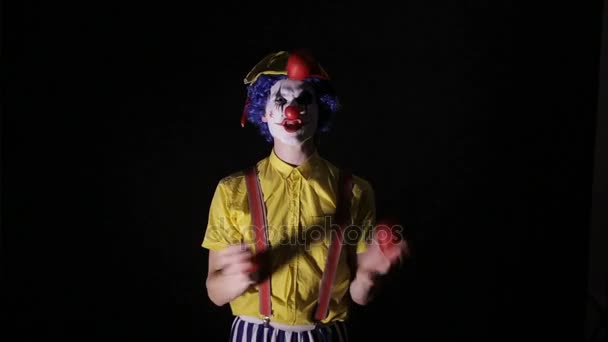 Een clown jongleert rode appels en toont zijn tanden. — Stockvideo