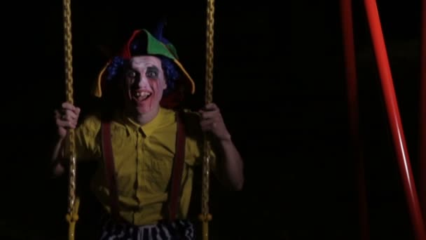 A clown with bloody makeup on swings. — Stock Video