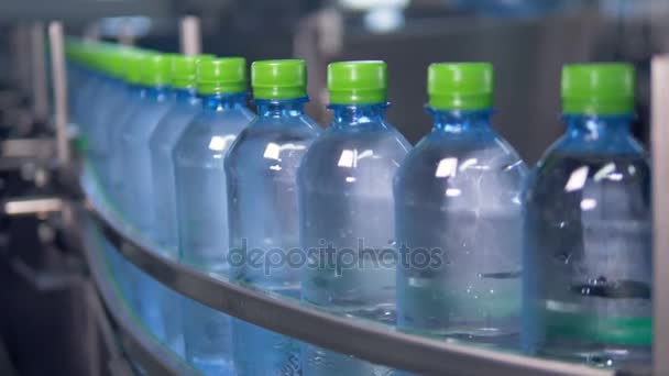 Las botellas de agua llenas y tapadas con pequeñas gotitas se mueven en una línea transportadora. 4K . — Vídeos de Stock