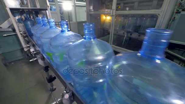 Groups of huge empty water bottles move on a conveyor line. 4K. — Stock Video