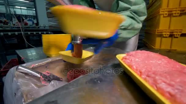 Een werknemer gebruikt veel plastic bakjes te verpakken gemalen vlees. — Stockvideo