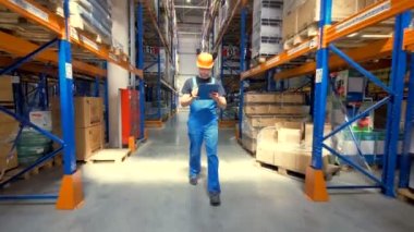 Bir işçi bir üniforma bir ambar koridoru geç yürüyor.