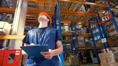 Bir adam bir depoda yüksek saklı öğeleri görmek çalışır ve notlar alır. 4k.
