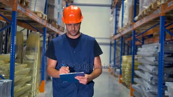 A warehouse supervisor takes notes on his clipboard. — Stock Video