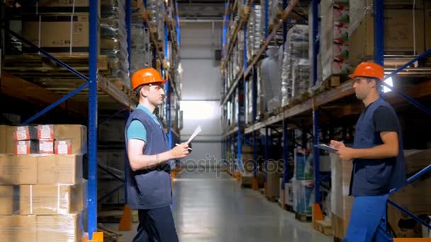 Two warehouse workers meet at a warehouse corridor. — Stock Video