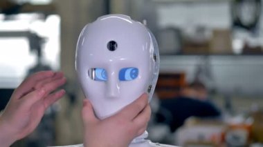 Bir teknisyen robotlar yüz kapak ekler.