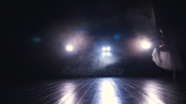 Una bailarina de ballet salta sobre un escenario oscuro . — Vídeo de stock