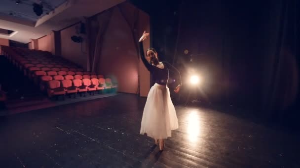 Una bailarina gira en el centro de un escenario vacío . — Vídeo de stock