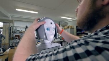 Bir mühendis gri plastik peruk robotlar başına yerleştirir..