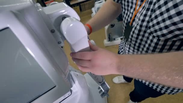 Un ingeniero cubre los brazos de los robots con una cubierta de plástico de acabado blanco. 4K . — Vídeos de Stock