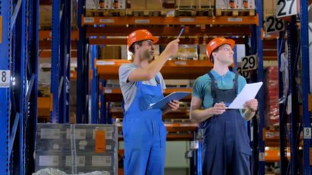在硬顶帽子，在一个巨大的工业仓库工作的工人。4 k. — 图库视频影像
