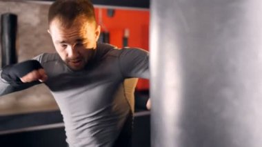 Bir adam bir kum torbasına yumruk gibi görünüyor.