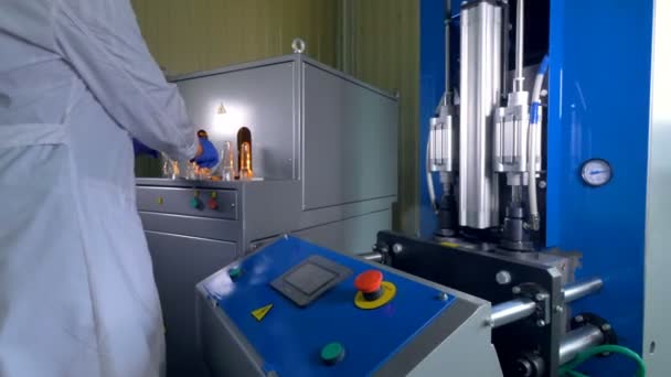 Un trabajador con una bata de laboratorio hace preformas en grandes botellas de PET . — Vídeos de Stock
