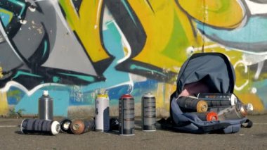 Bir grafiti duvarının yakınında bir sırt çantası içinde kullanılan sprey boya kutuları.