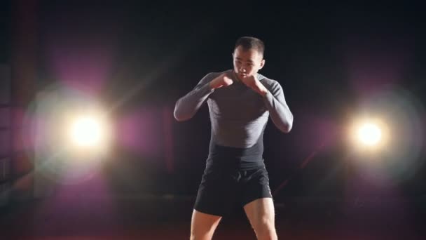 一位拳击手炫耀他的出拳和踢在深色背景上. — 图库视频影像