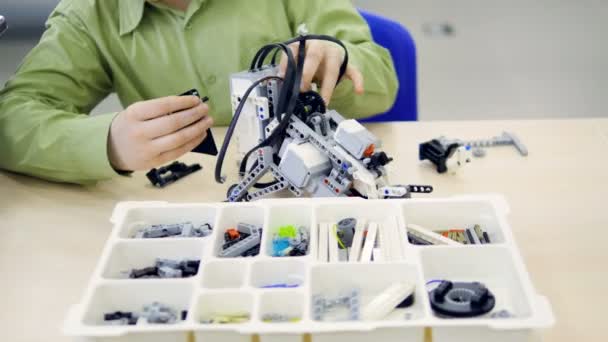 Anak sekolah muda merakit model kit dari robot futuristik. 4K . — Stok Video
