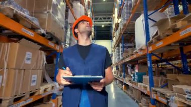 Elinde dosya olan bir işçi bir ambar inceler.