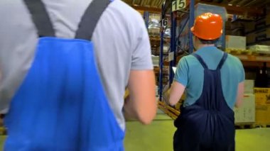 Erkek ambar çalışanları yürüyüş geçmiş birkaç depo rafları.