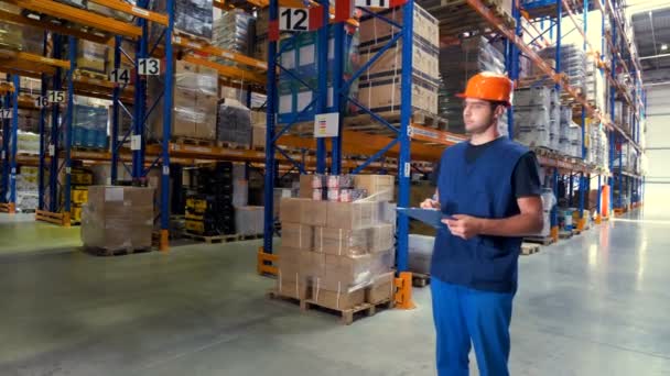 A warehouse employee looks around different aisles. — Stock Video
