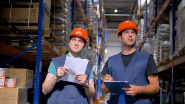 Twee magazijnmedewerkers praten en notities. — Stockvideo