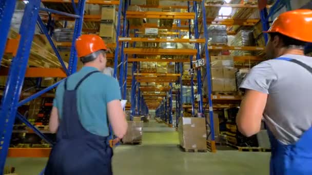 Two inspectors walk through a giant warehouse. — Stock Video