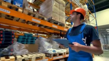 Bir işçi bir kask ve bir depoda yürür.