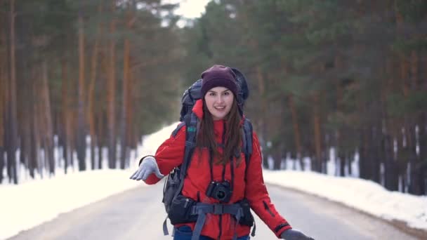 Eine fröhliche Touristin beginnt ihre Reise und läuft die Straße entlang durch den sonnigen Winterwald. hd. — Stockvideo