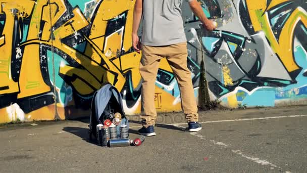 Un artista de graffiti se prepara para usar una lata de pintura amarilla . — Vídeo de stock