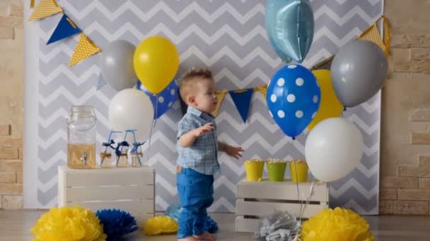 Ένα μικρό παιδί γελά και κτυπά στο δεμένα μπαλόνια. — Αρχείο Βίντεο