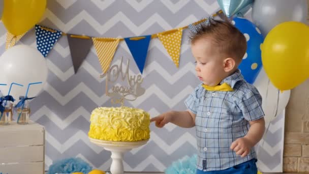 Un bambino mette un dito dentro una torta di compleanno . — Video Stock