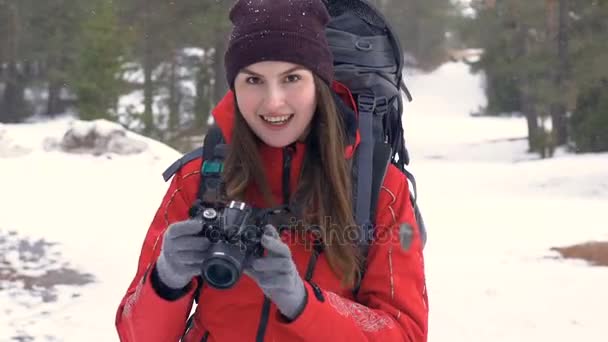 Turista feliz con cámara fotográfica haciendo fotos en el bosque mientras nieva . — Vídeos de Stock