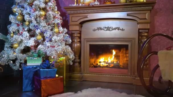 Fondo de año nuevo. Una cálida chimenea con vistas a un árbol de Navidad durante la noche de año nuevo . — Vídeos de Stock